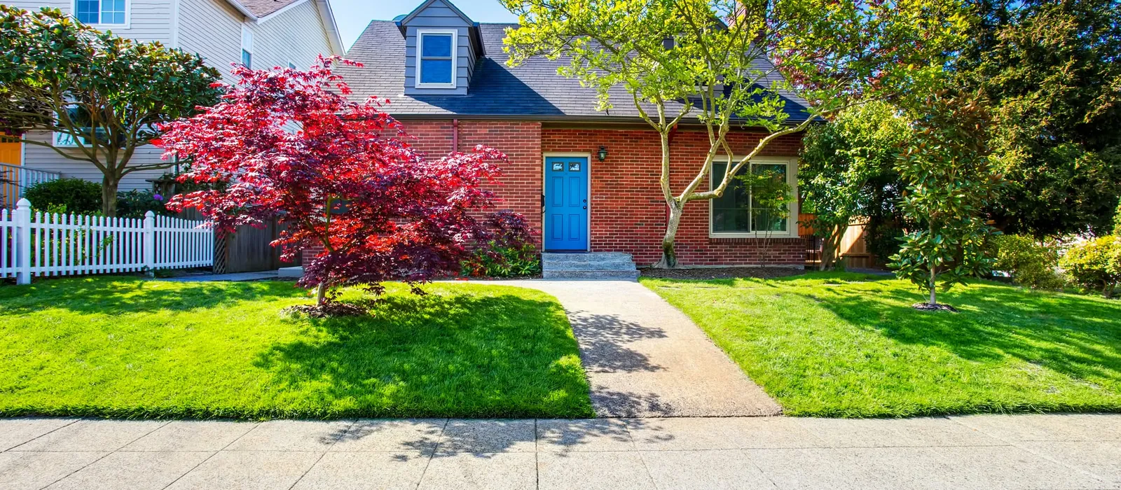 Red brick house with a tile roof and a maple tree