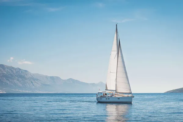 Sailboat on calm water with mountains behind