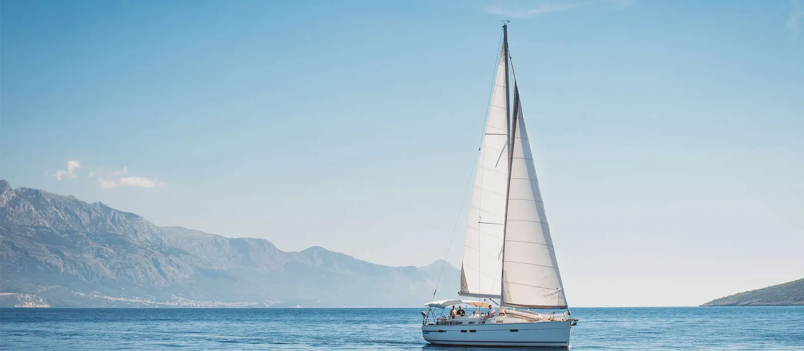 Sailboat on calm water with mountains behind