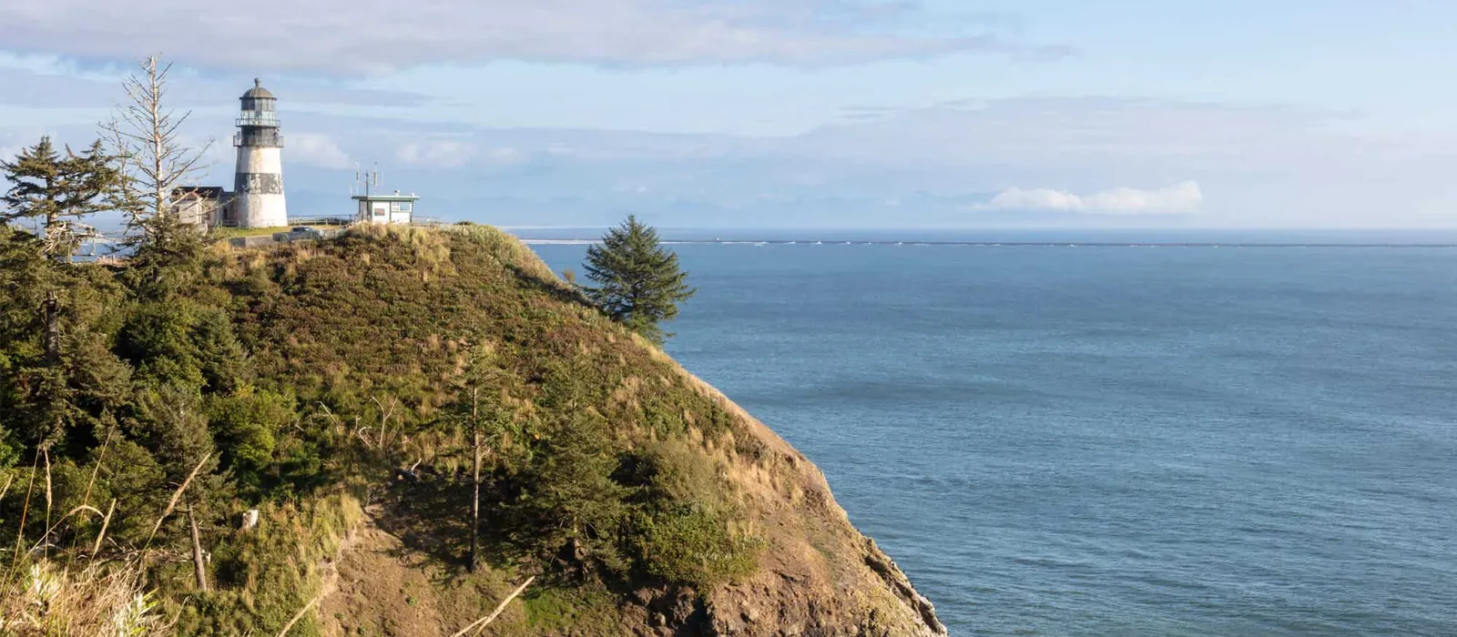 Lighthouse on a wooded headland above the ocean