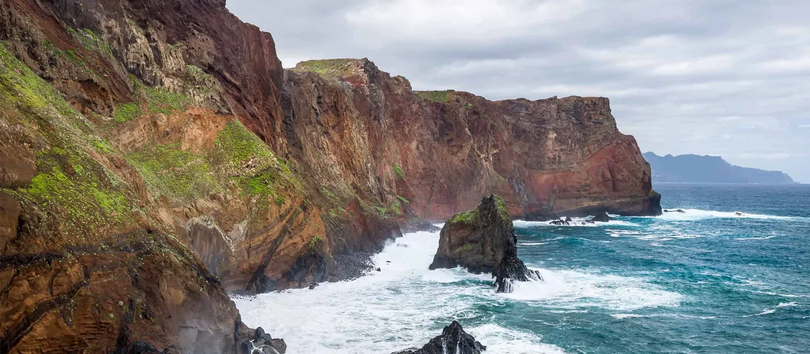 Waves breaking against red sea cliffs