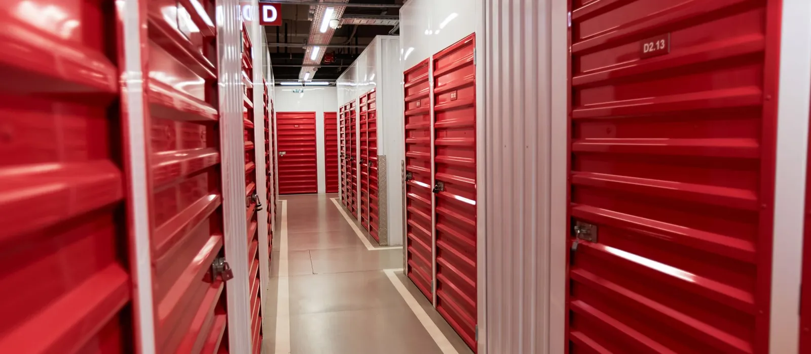 Corridor of locked red roll-up doors in a self-storage facility
