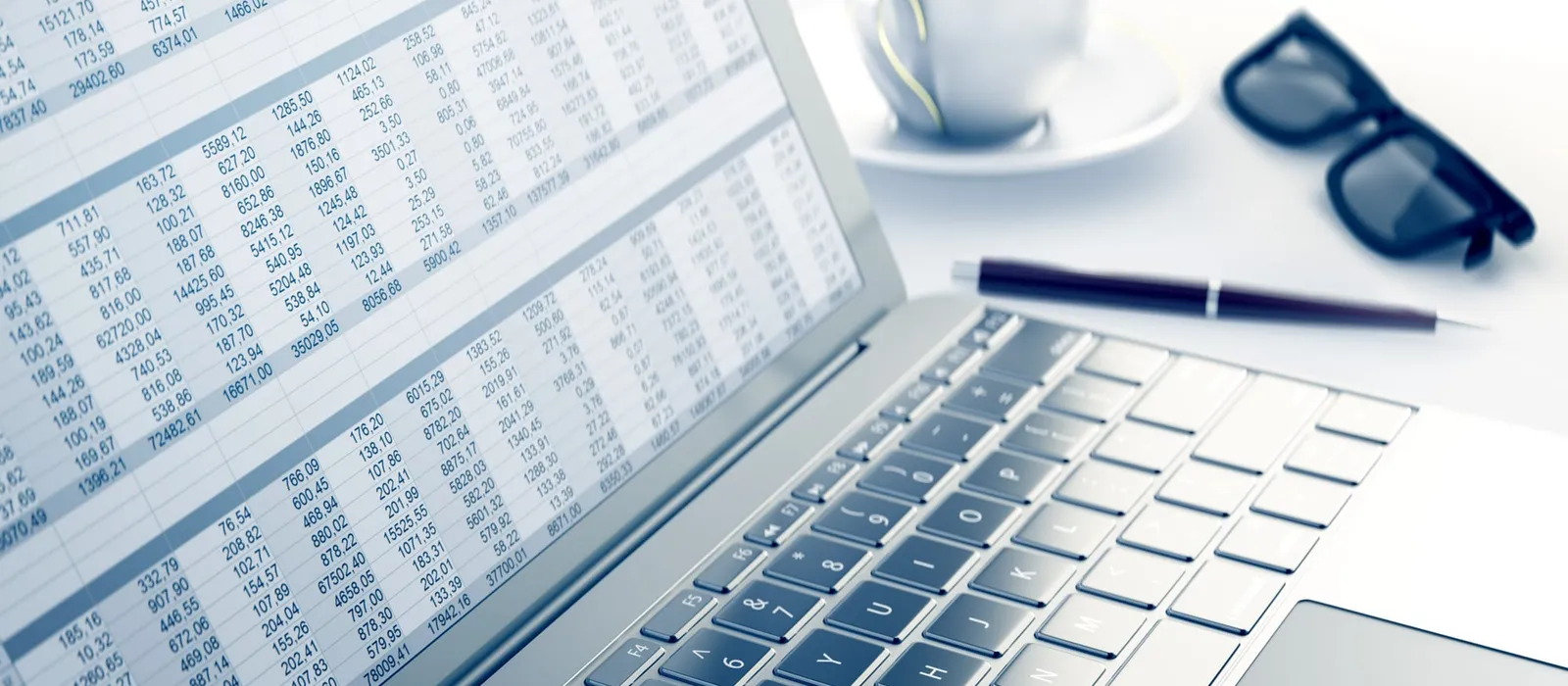 Spreadsheet open on a laptop beside a calculator