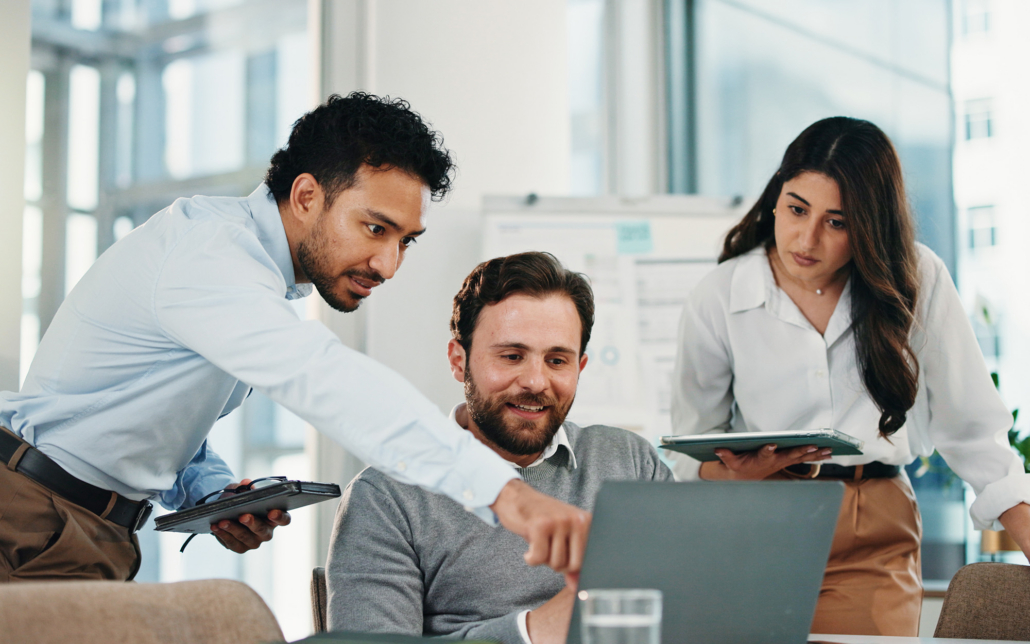 Group Of Workers Looking At Laptop In Office
