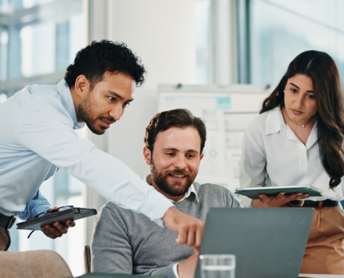 Group Of Workers Looking At Laptop In Office