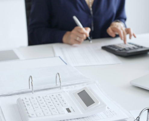 Person Using Calculator To Do Taxes